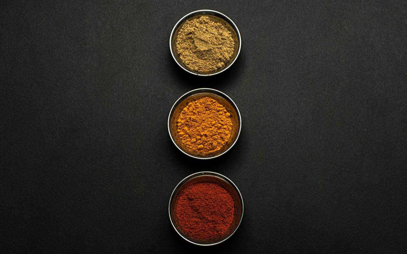 Vibrant, graded spice powders in metal bowls ready for quality inspection